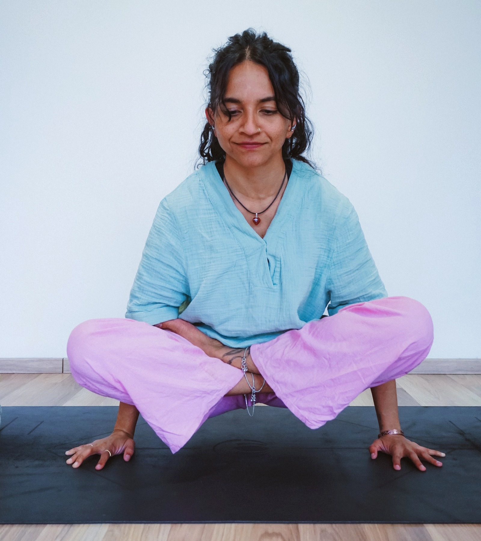 Priyanka balanced in a seated squat, hands grounded on the mat, justnow YOGA, Prague